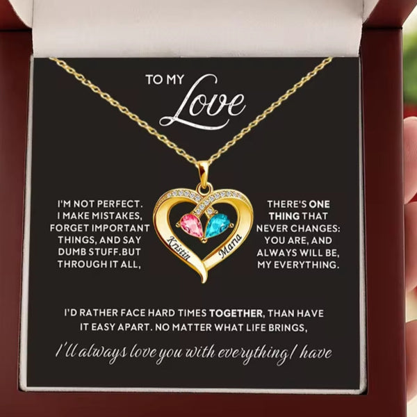 A gold heart pendant necklace with a pink and blue gemstone, presented in a gift box with a sentimental message card addressed 'TO MY Love'.